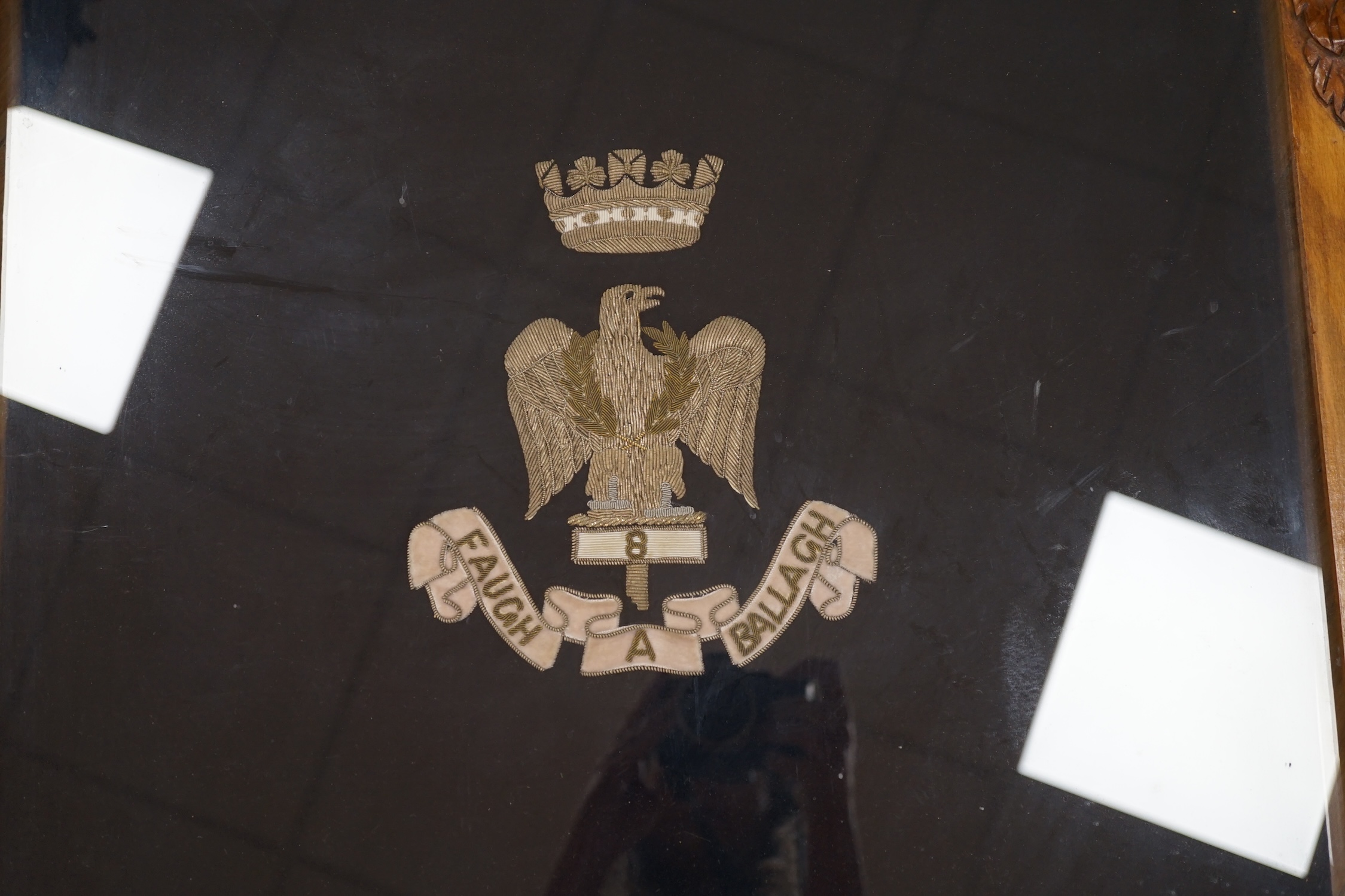 A framed bandsman’s banner of the Royal Irish Fusiliers, a crowned eagle in silver thread, over ‘8 Faugh A Ballagh’, 64 x 52cm, in a carved oak frame. Condition - good.